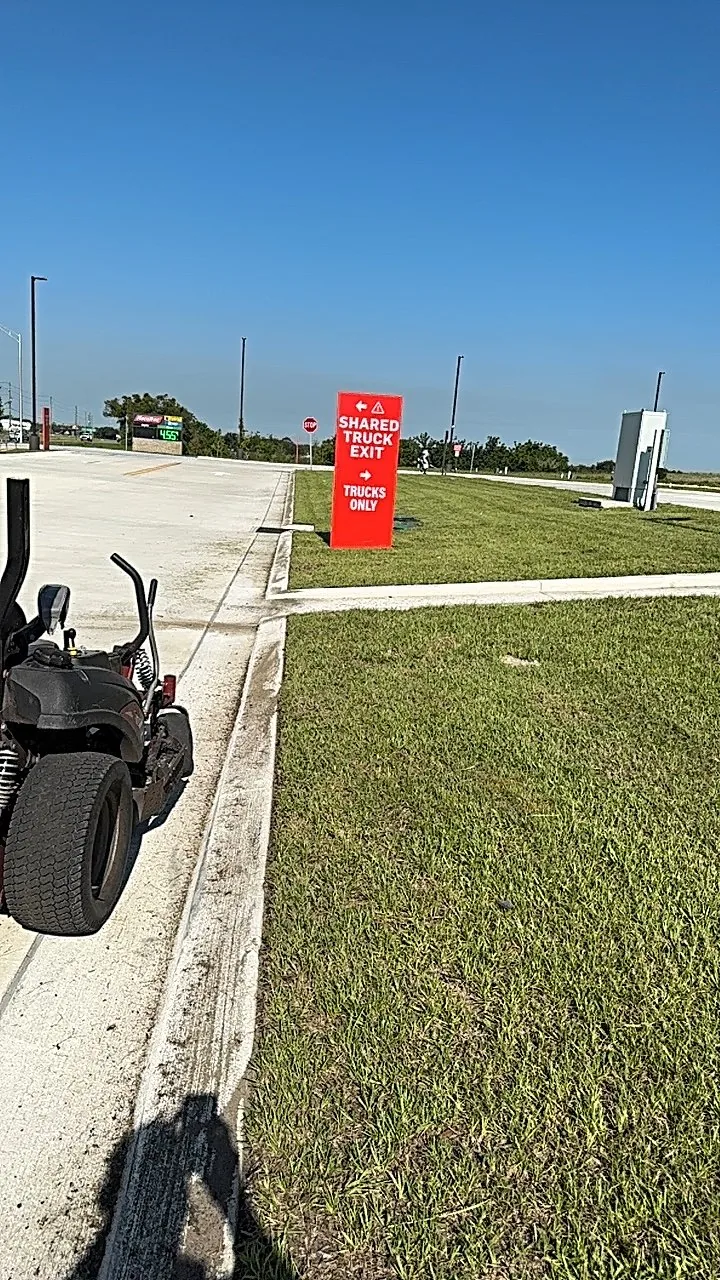 Mowed commercial frontage beside a shared truck exit