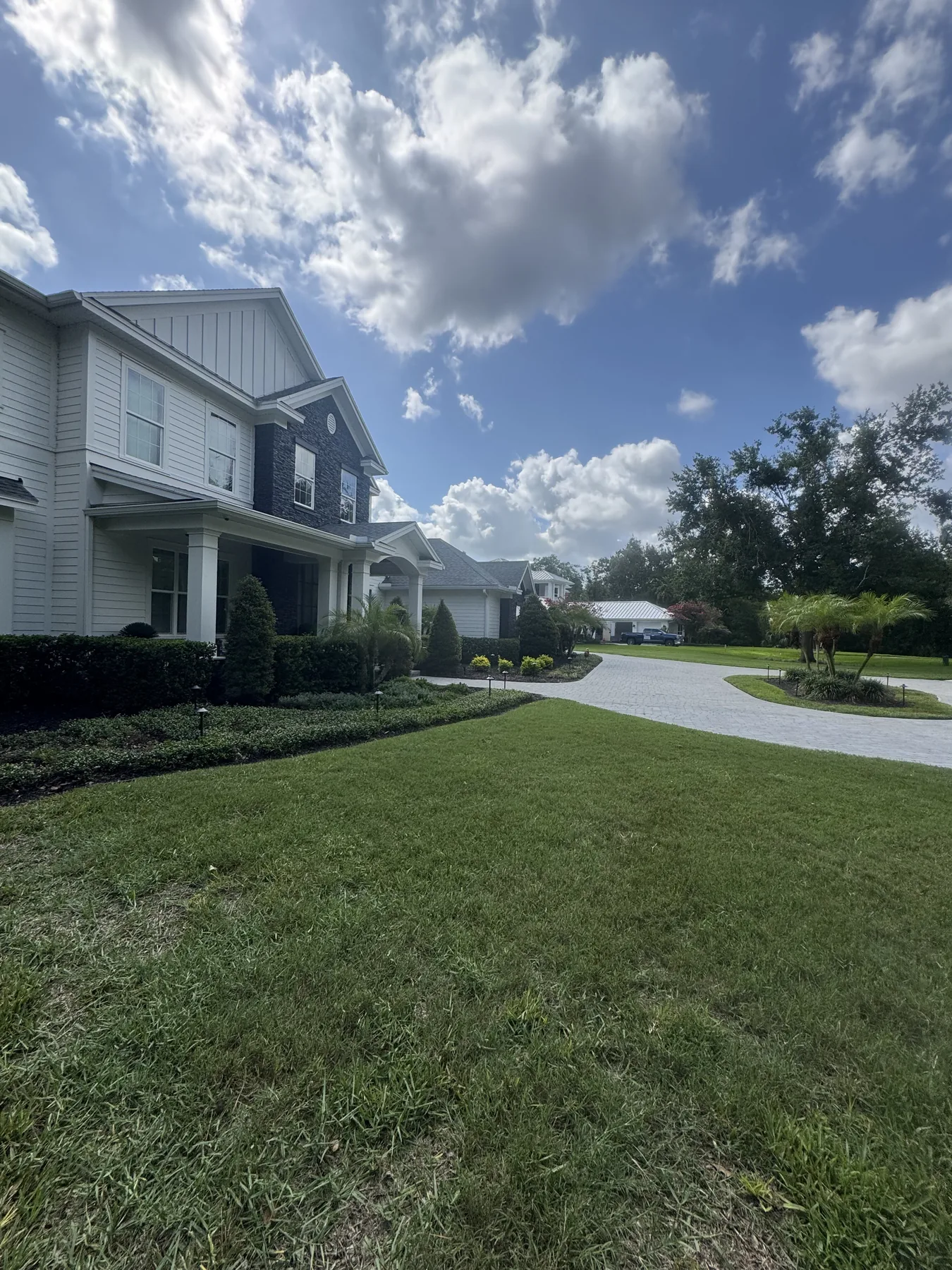 Large residence with maintained lawn and paver driveway